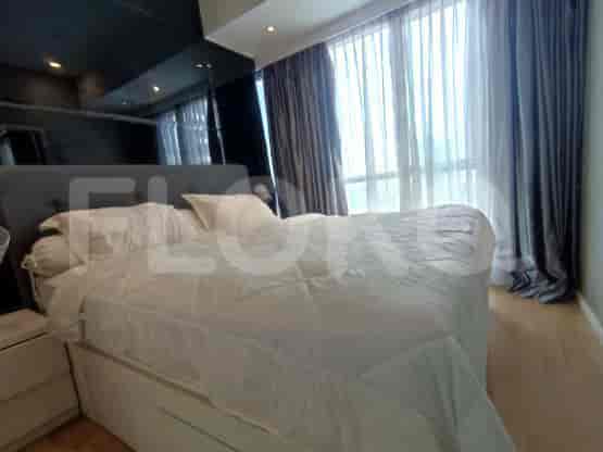 A bedroom with a large bed and window curtains.