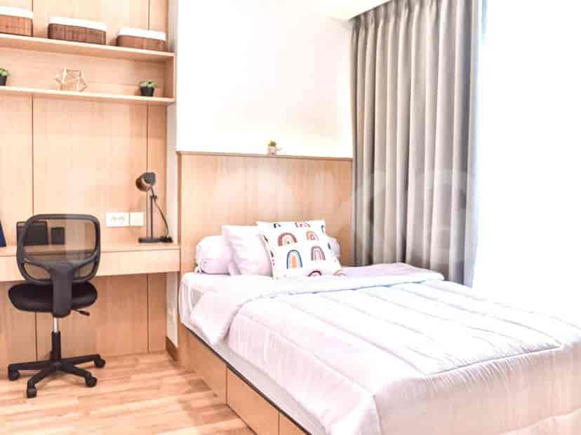A bedroom/study space featuring a wooden bed, desk, and small shelf.
