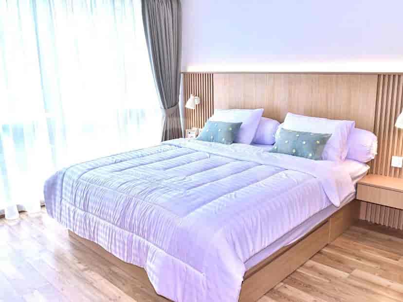 A bright bedroom featuring a wooden headboard, bed with white bedding, and large window.