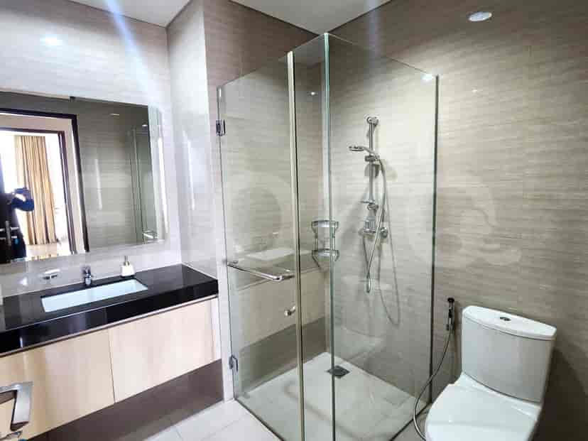 Kamar mandi modern dengan pancuran berkaca, meja rias, dan skema warna netral.