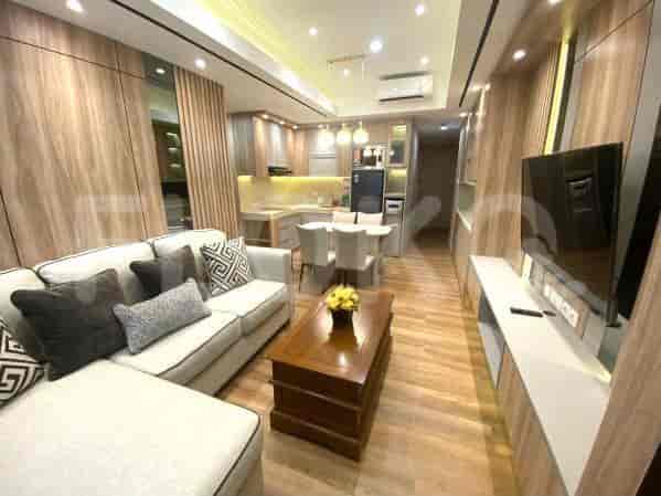 Living room with kitchen view, featuring a sofa, TV, and dining area.