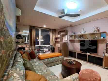Ruang tamu yang luas dengan sofa berbentuk L, TV pintar, dan jendela besar dengan pemandangan kota.