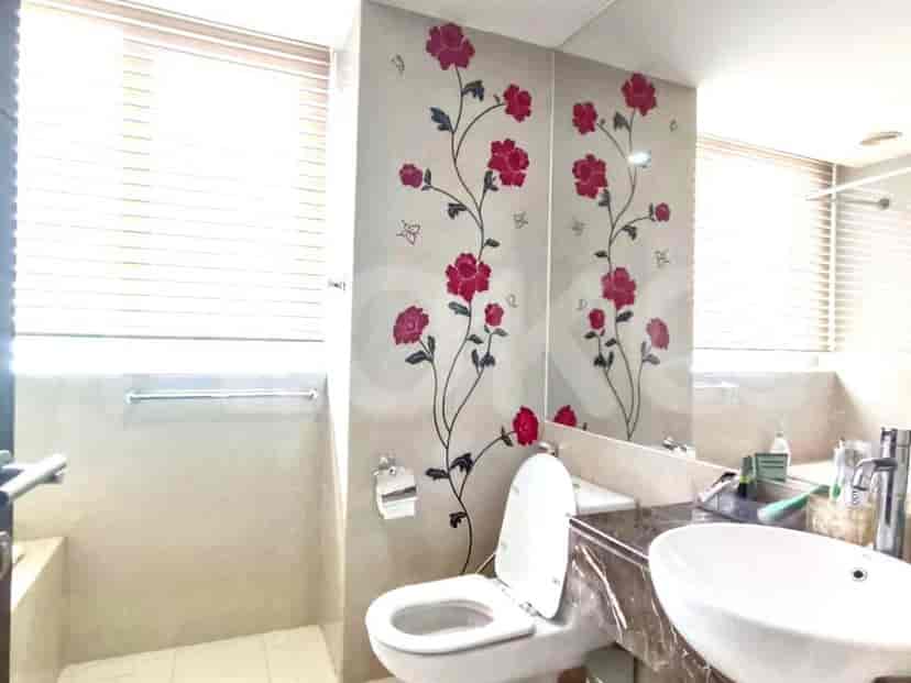 Bathroom with a toilet, sink, floral wall decor, and a mirror.