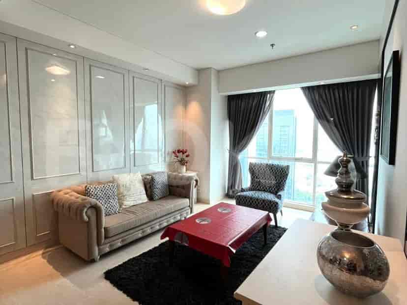 Ruang tamu dengan sofa krem, meja merah, dan kursi bermotif.