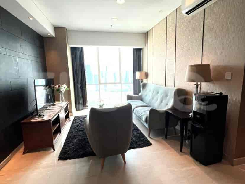 Ruang tamu modern dengan sofa abu-abu, TV, dan pemandangan kota.