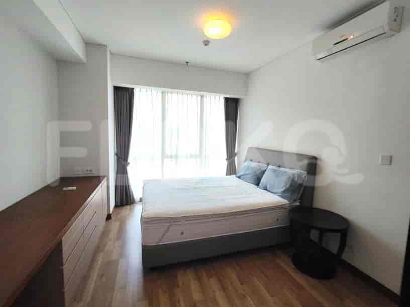 A bedroom with a bed, nightstand, and large window.