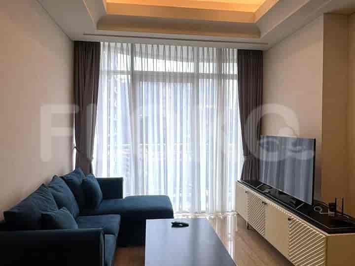 A modern living room with a blue L-shaped sofa, a TV on a cabinet, and large windows with curtains.