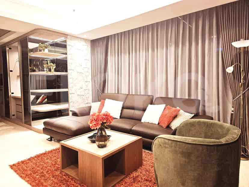 Ruang tamu modern yang menampilkan sofa kulit cokelat, karpet area, dan rak built-in.