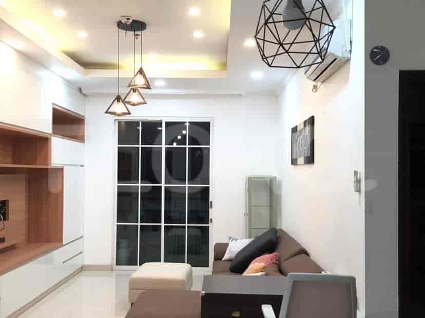 A well-lit living room with a modern design, featuring a sofa, large window, and contemporary lighting.