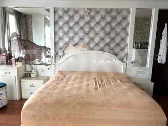 Kamar tidur dengan tempat tidur, meja samping tempat tidur, dan dinding aksen cermin.