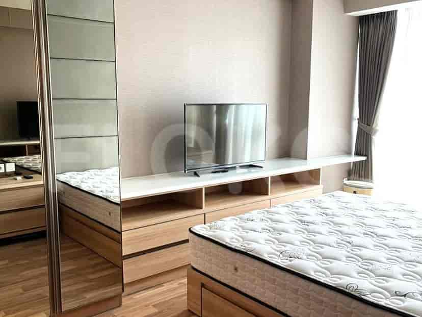 Kamar tidur modern dengan TV, penyimpanan built-in, dan tempat tidur besar.