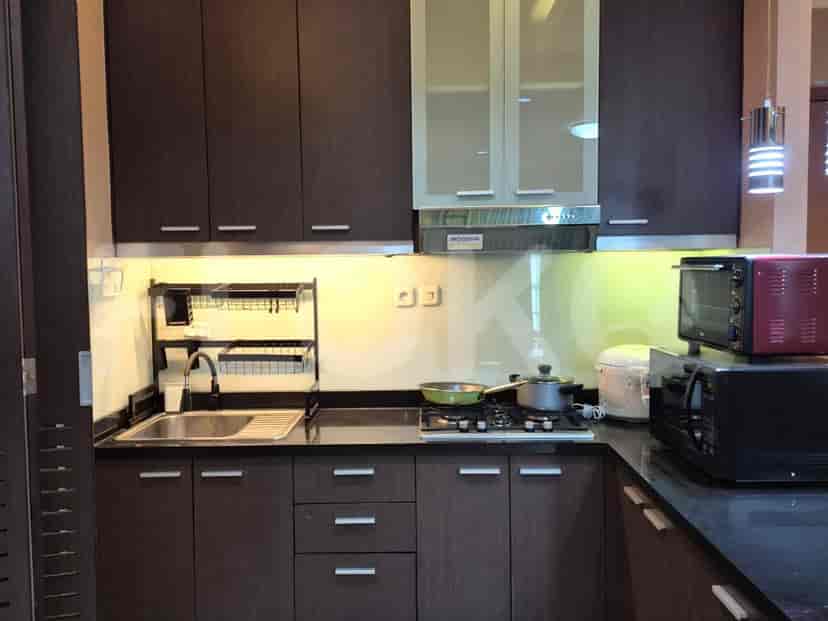 A modern kitchen with dark wooden cabinetry, stainless steel appliances, and a microwave.
