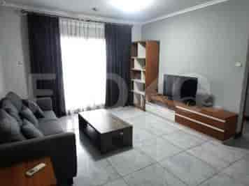 A living room with a grey sofa, coffee table, and entertainment unit with a TV.