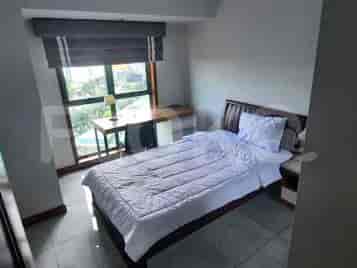 A bedroom with a single bed, wooden desk, and a large window.