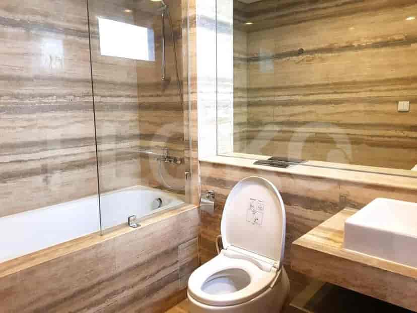 A modern bathroom featuring a bathtub, toilet, sink, and marble-patterned walls.