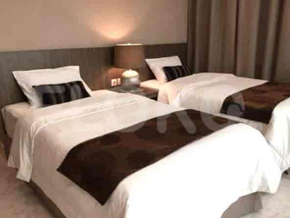 A bedroom with two twin beds, bedside table, and lamps.