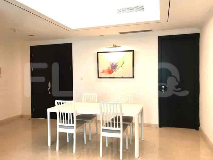 A dining area with a white table and chairs, and two black doors.