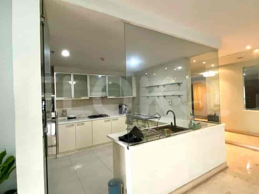 A modern kitchen with cream cabinets, a gas stove, a sink, and glass partitions.
