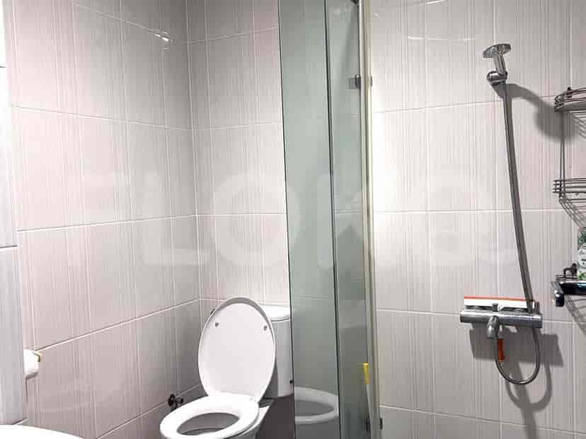 A modern bathroom with a toilet, glass-enclosed shower, and tiled walls.
