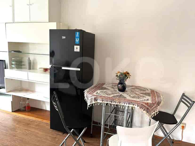 A compact kitchen and dining area with a black refrigerator, small dining table with chairs, and modular kitchen cabinets.