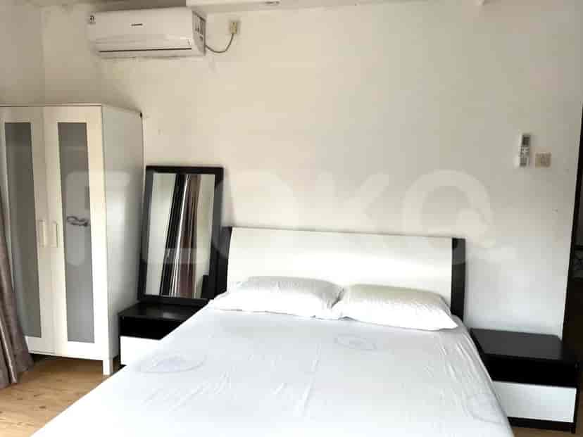 A bedroom with a queen-sized bed, bedside tables, a wardrobe, and an air conditioning unit.