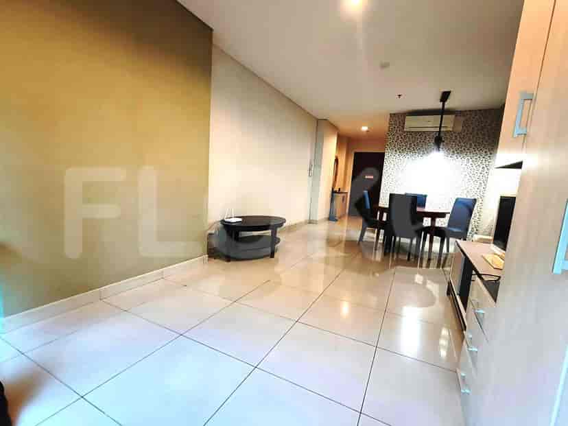 A living and dining area with a dark round coffee table, dining table with four chairs, and a patterned accent wall.
