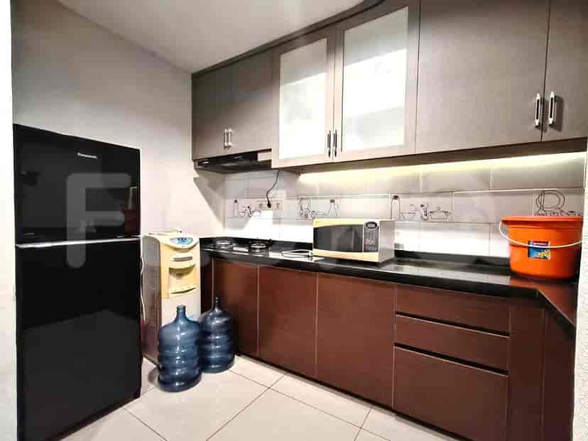 A kitchen with a black refrigerator, water dispenser, microwave, stove, and cabinetry.