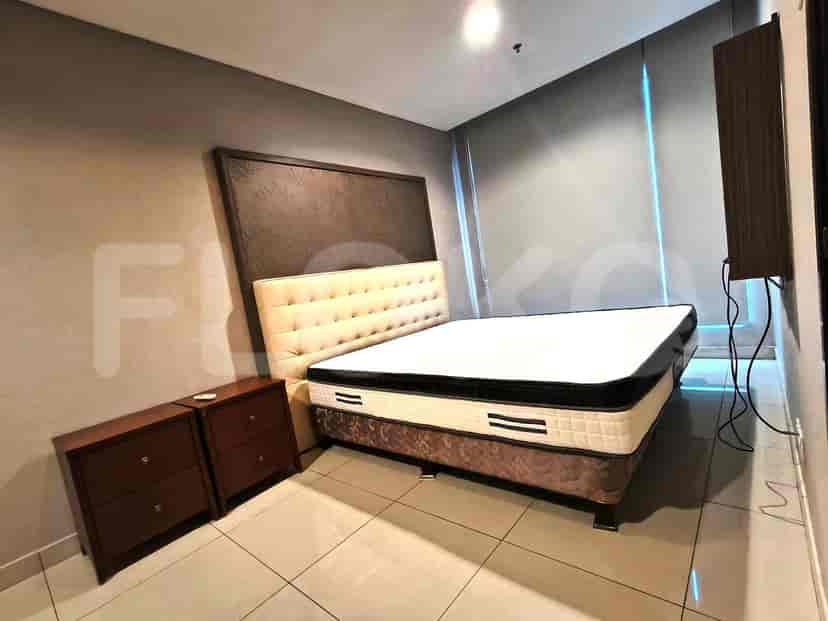A bedroom featuring a large bed with a tufted headboard and two dark wood nightstands.