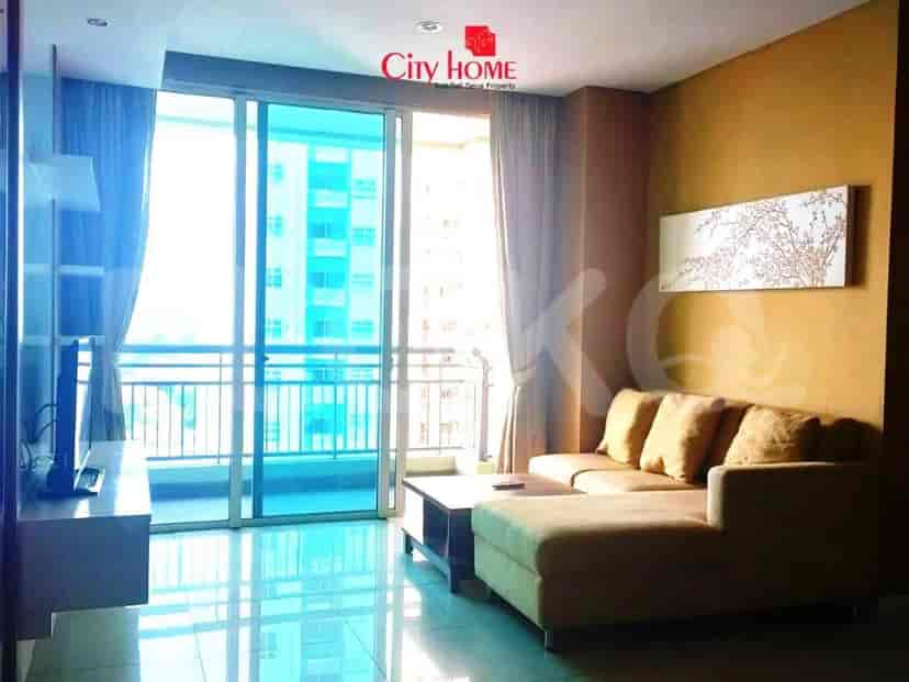 A living room with a sectional sofa, coffee table, and a balcony with a city view.