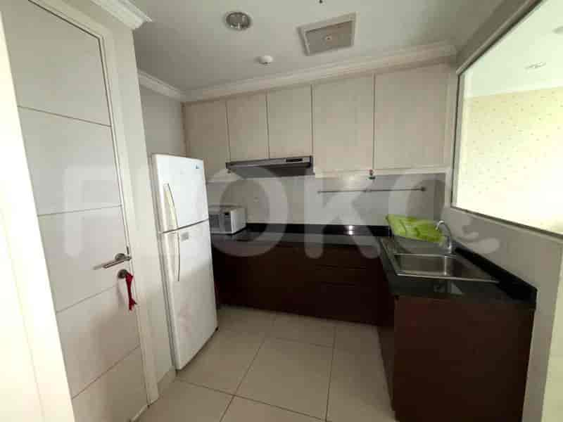 Dapur dengan peralatan putih, meja dapur gelap, dan lemari kayu.