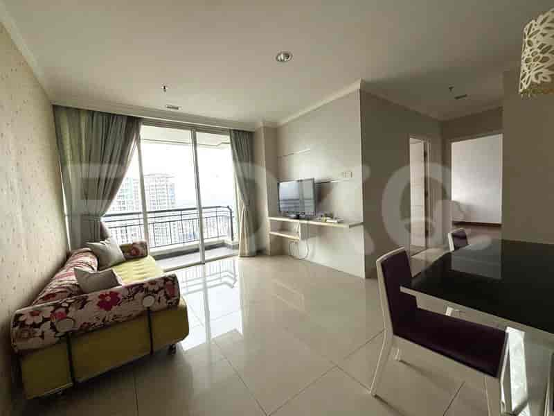 Ruang tamu dengan sofa berpola, meja makan, dan jendela besar yang menghadap pemandangan kota.