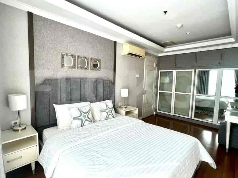 Kamar tidur utama dengan tempat tidur king-size, kepala tempat tidur berlapis, meja samping tempat tidur, dan lemari besar.