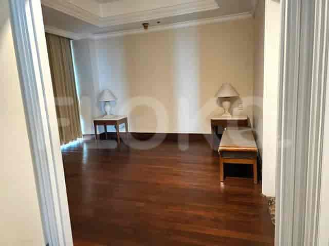 An empty living area with wooden floors, two side tables with lamps, and a bench.