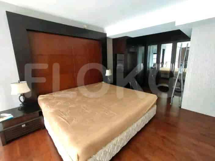A bedroom featuring a king-size bed with a wooden headboard, bedside tables, and a closet.