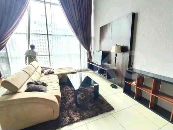 A modern living room with a large sectional sofa, a coffee table, a TV console, and floor-to-ceiling windows.