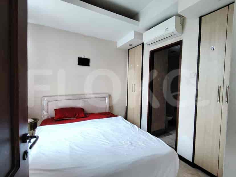 A bedroom with a bed, nightstand, air conditioner, and two tall wardrobes.