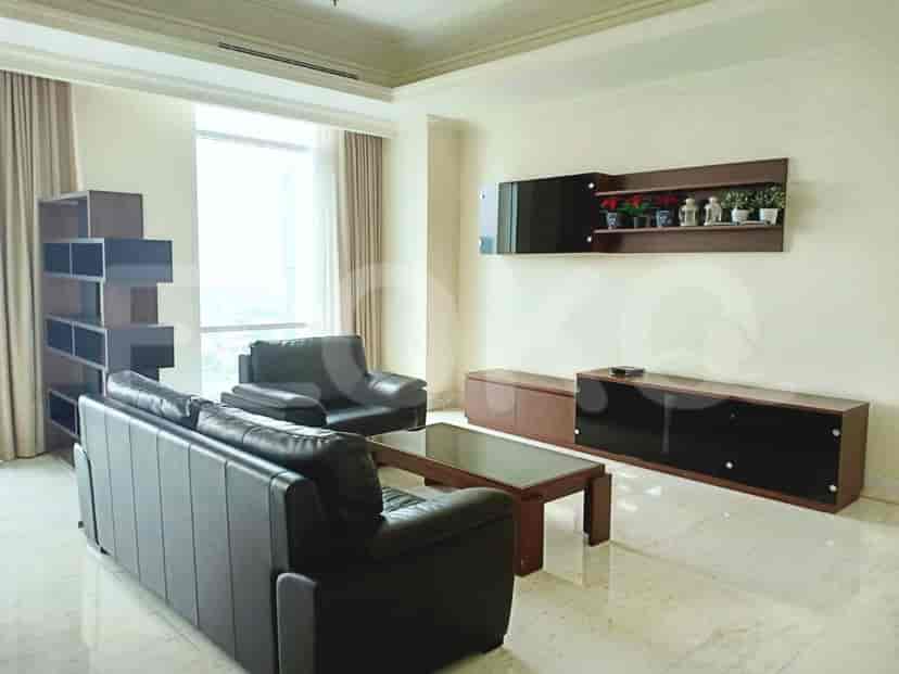 A modern living room with dark leather sofas, a coffee table, and a wall-mounted entertainment unit.