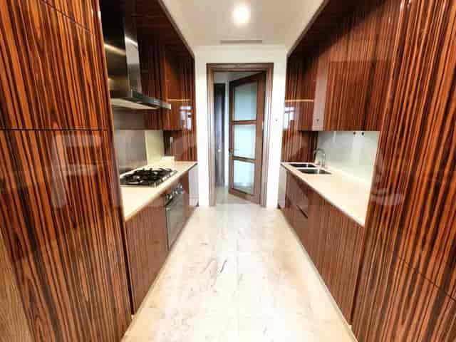 Dapur sempit modern dengan lemari kayu gelap dan peralatan stainless steel.