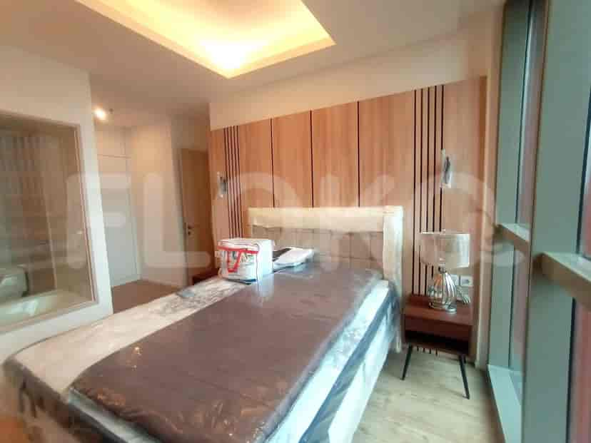 A bedroom with a queen-sized bed, wooden wall paneling, and large windows.