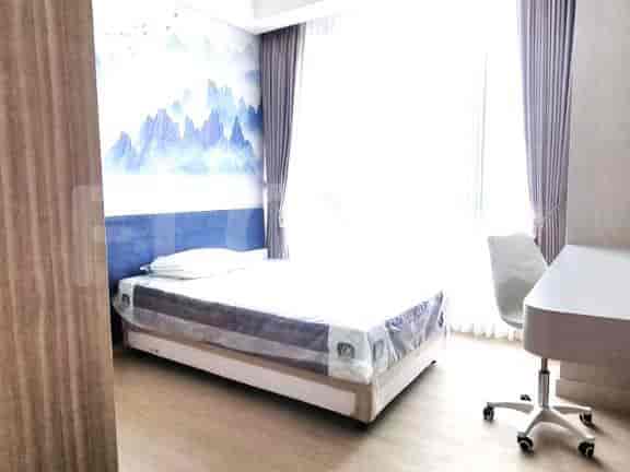 Kamar tidur dengan tempat tidur tunggal, meja, dan jendela dengan tirai tipis.
