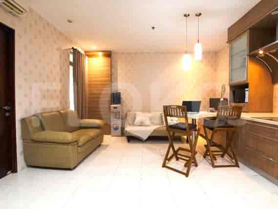 A beige sofa and a foldable sofa are in the living area, with a water dispenser and a small dining area.