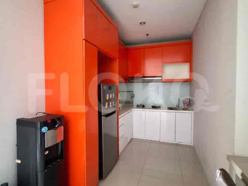 A compact kitchen with orange and white cabinets, a refrigerator, and a stove.