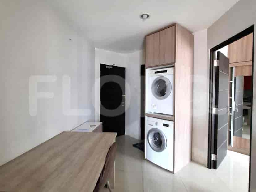 A utility area with stacked washing machines and dryers, and a wooden table.