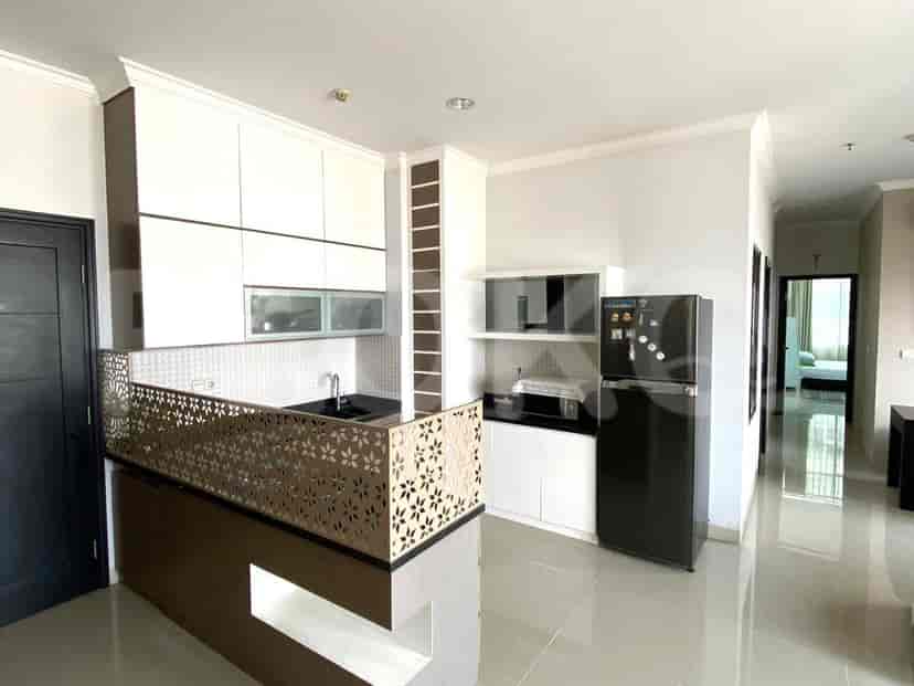 A modern open-plan kitchen with white and brown cabinetry, a black refrigerator, and a microwave.
