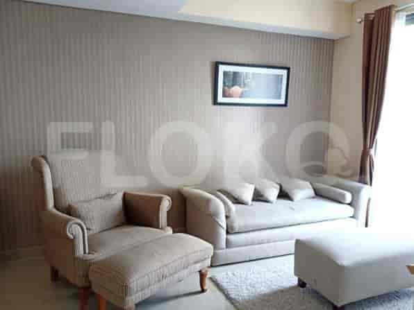 Sebuah ruang tamu dengan sofa, kursi berlengan dengan ottoman, dan meja kopi.