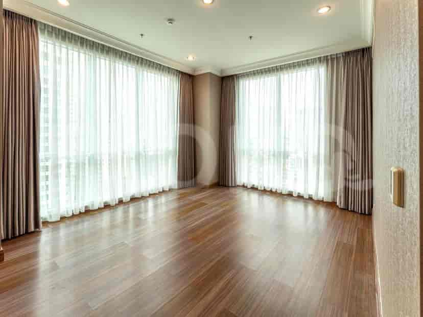 Kamar tidur dengan lantai kayu, jendela besar dengan gorden tipis, dan dinding berwarna netral.