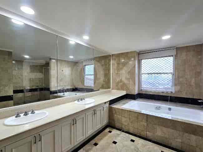 A large bathroom with a double vanity, a bathtub, and tiled walls.