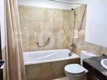A bathroom with a bathtub, toilet, and sink, tiled walls, and a shower curtain.