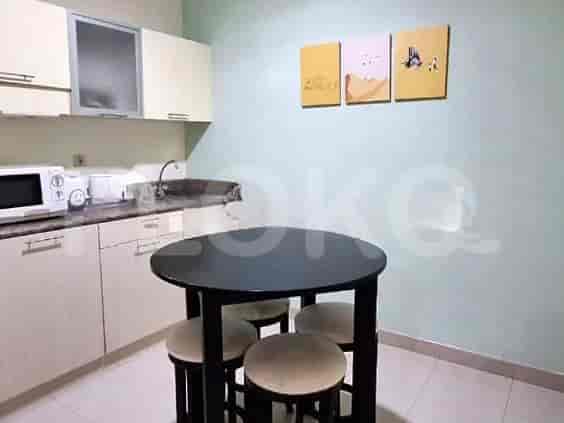 A compact kitchen with white cabinets, a microwave, sink, and a small round dining table.