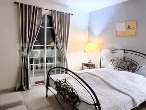 A bedroom with a queen-size bed, a metal frame, and a large window with curtains.